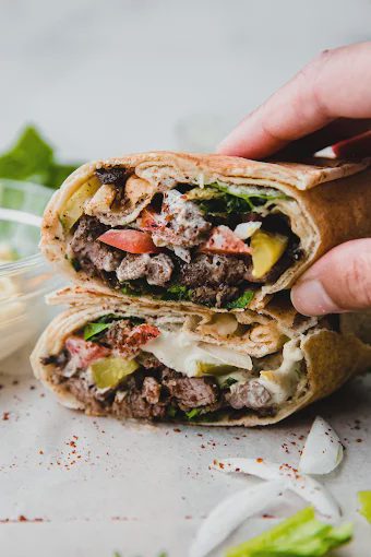 Lamb shawarma wrap cut in half with vegetables.